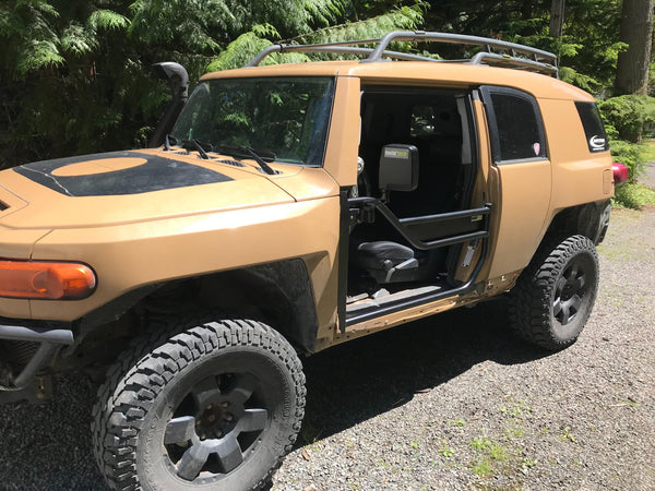 Tan FJ Cruiser with black Metal Tech tube doors installed, shown from front passenger side outdoors.