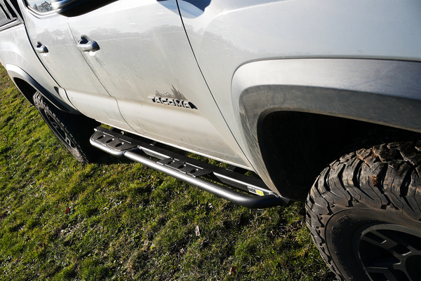 Black Metal Tech 4x4 rock slider installed on the side of a white 2016 Tacoma short bed 4-door truck.