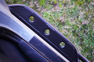 Close-up of black metal rock slider mounting bracket with three circular holes on 2016 Tacoma short bed truck.
