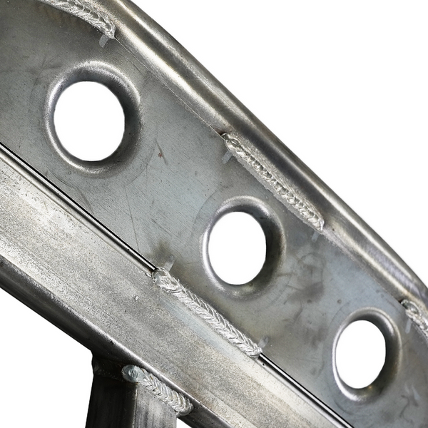 Close-up of metal rock slider section showing welds and circular cutouts on steel plate.