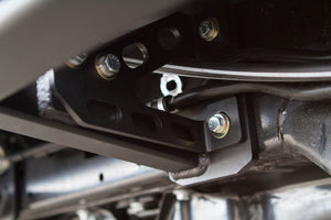 Close-up of black metal bracket and bolts on the underside of a 2010 4Runner with trail rock sliders installed.