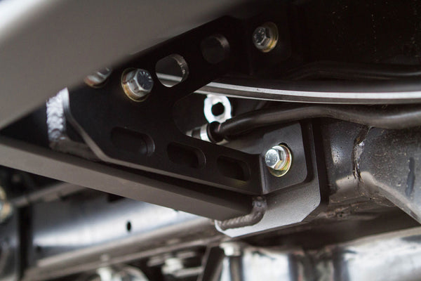 Close-up of black metal bracket and bolts on the underside of a 2010 4Runner with trail rock sliders installed.
