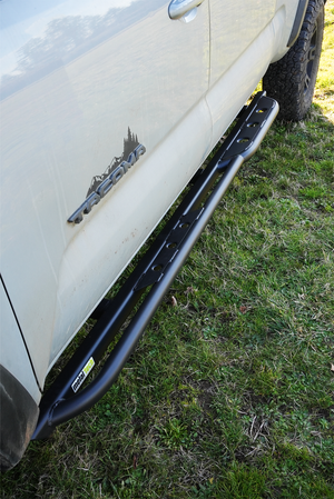 Black Metal Tech rock slider installed on the side of a white 2016 Tacoma short bed 4-door truck.