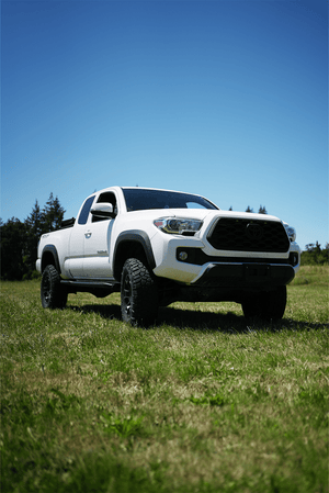 White 2016 Toyota Tacoma Access Cab with Metal Tech 4x4 black side sliders installed, parked on grass.