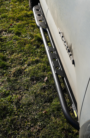 Close-up of black Metal Tech 4x4 rock slider installed on 2016 Tacoma short bed, showing textured finish and mounting brackets.