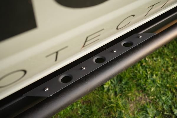 Close-up of sniper gray cerakoted step plate mounted on vehicle side rail with grass background.