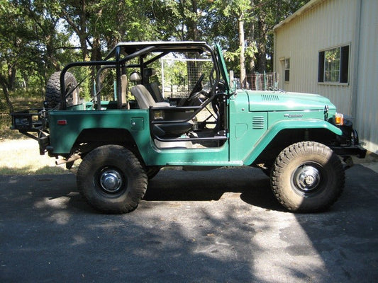 Side view of green FJ40 Land Cruiser with open doors and installed black Jackson roll cage.