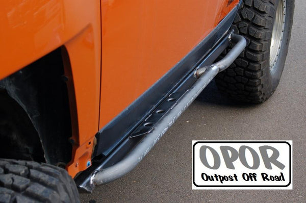 Close-up of metal rock sliders installed on orange FJ Cruiser, showing side protection and rugged tire.