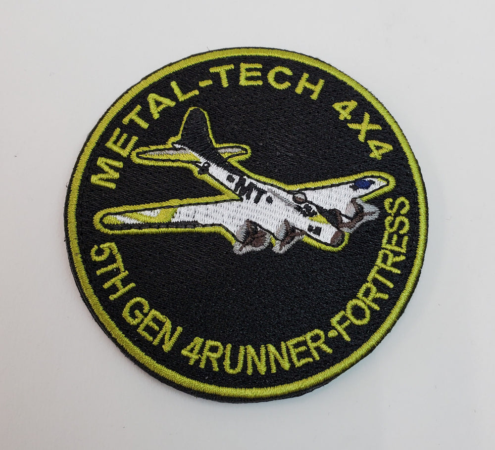 Round embroidered patch with a white airplane and yellow text reading "Metal-Tech 4x4 61st Gen 4Runner Fortress" on black background.