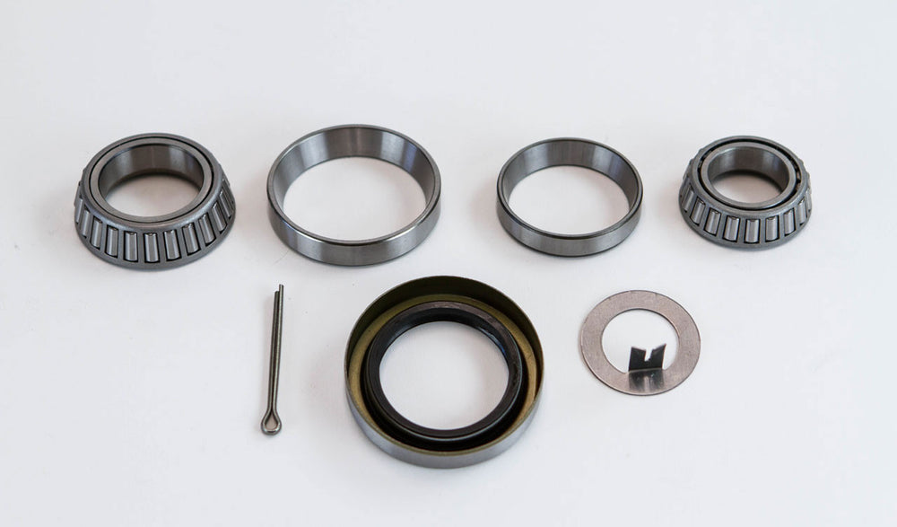 Replacement swing out arm bearing service kit with tapered bearings, seals, and metal washers laid out on white background.