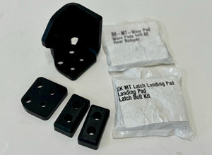 Black metal and rubber components of the landing pad system left side latch with labeled packaging bags.