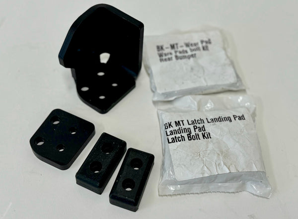 Black metal and rubber components of the landing pad system left side latch with labeled packaging bags.