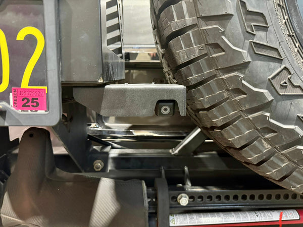 Close-up of rear camera relocation kit installed near spare tire on GX470 or GX460 rear bumper.