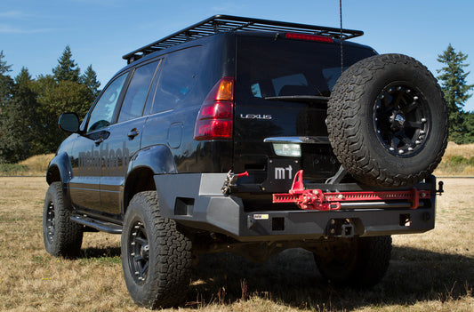 Black rear swing-out bumper with mounted license plate holder and spare tire on a black Lexus SUV.