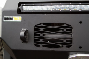 Close-up of Metal Tech winch hole cover installed on Fortress bumper with black powder coat finish and LED light bar above.