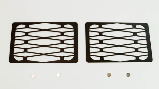 Pair of black metal tech winch hole covers with geometric cutouts for Fortress bumper, shown flat on white background.
