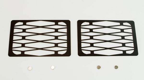 Pair of black metal tech winch hole covers with geometric cutouts for Fortress bumper, shown flat on white background.