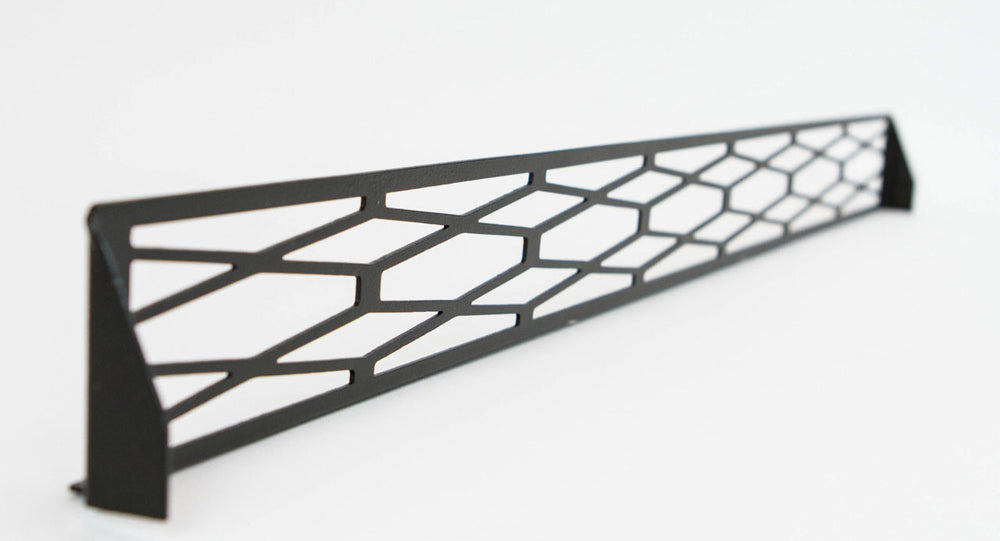 Black metal front bumper grill insert with geometric cutout pattern, angled view on white background.