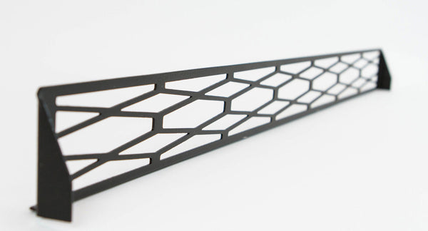 Black metal front bumper grill insert with geometric cutout pattern, angled view on white background.