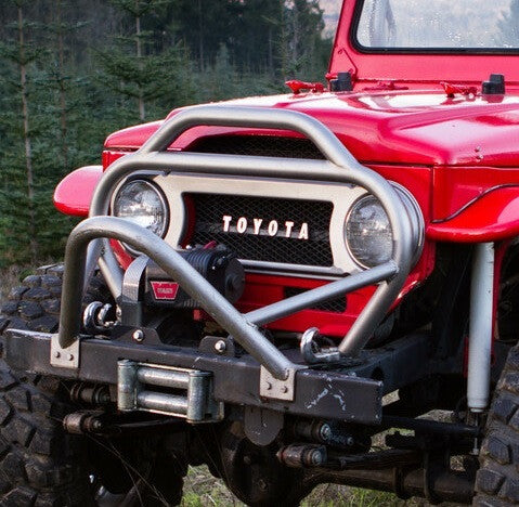 Close-up of red Toyota FJ40 Land Cruiser front with installed Metal Tech stinger bumper and winch.