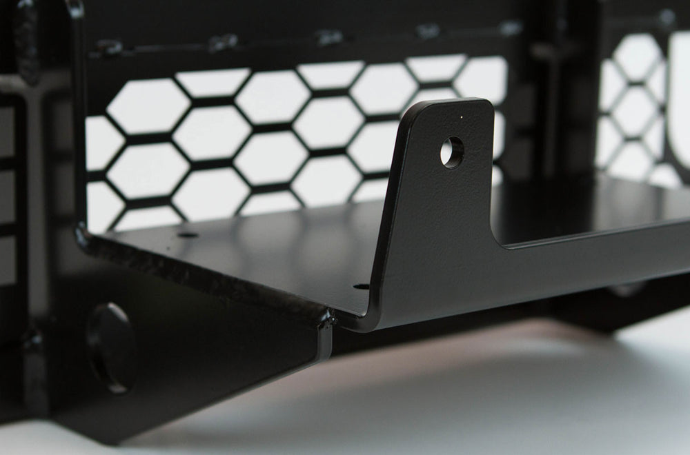 Close-up of black metal winch mount bracket with hex-patterned backing, designed for FJ Cruiser front tube bumper.