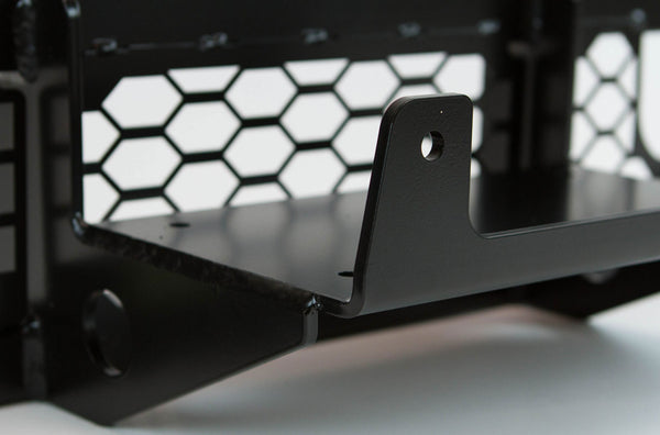 Close-up of black metal winch mount bracket with hex-patterned backing, designed for FJ Cruiser front tube bumper.