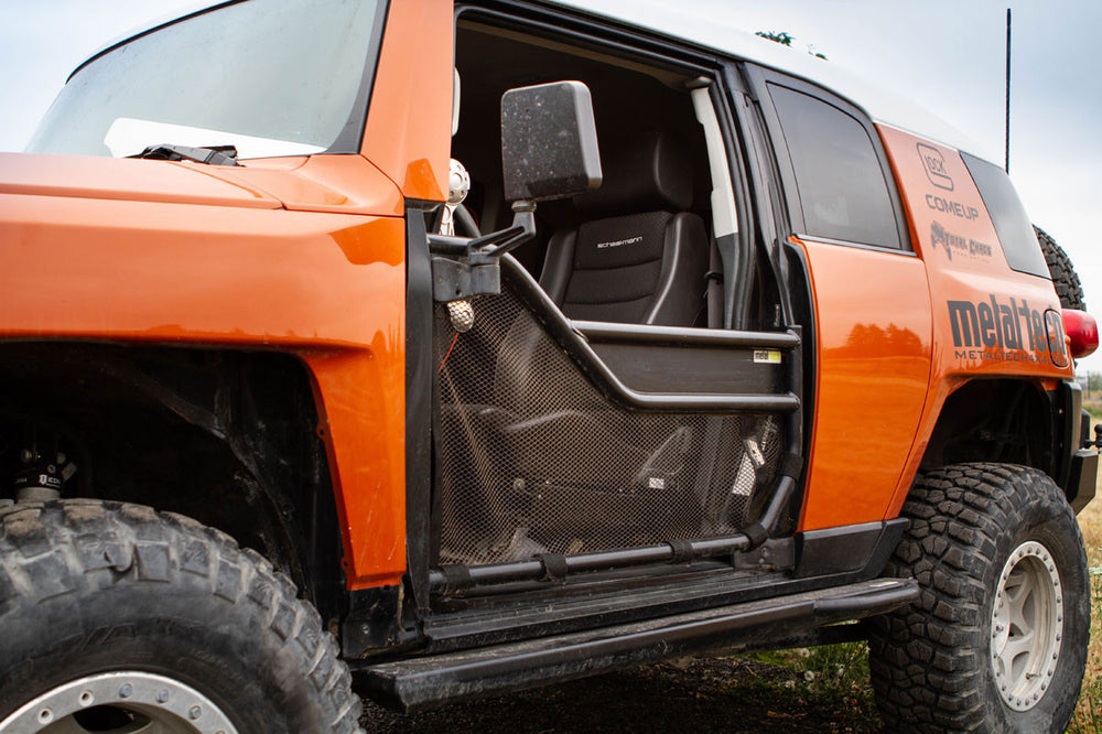 Close-up of orange FJ Cruiser with Metal Tech black tube door and mesh panel installed on driver side.