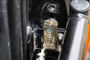 Close-up of metal latch mechanism on black frame of FJ Cruiser tube door showing bolts and mounting points.