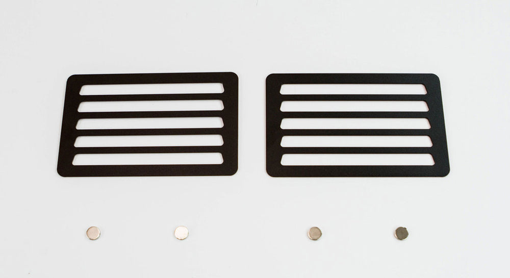 Pair of black metal winch hole covers with horizontal slots and four small round magnets on white background.