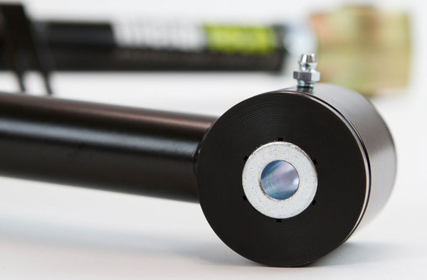 Close-up of black metal rear upper link with silver bushing and grease fitting for 100 Series Land Cruiser LX470 suspension.