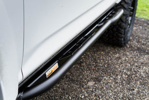Close-up of black Metal Tech 4x4 rock slider installed on 2010 4Runner side with gravel ground visible.