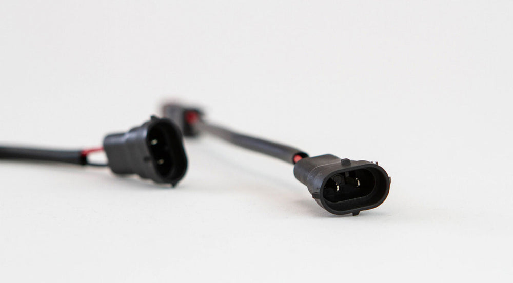 Close-up of black and green Toyota fog light harness connector for 2010 4Runner, Tundra, Tacoma on white background.