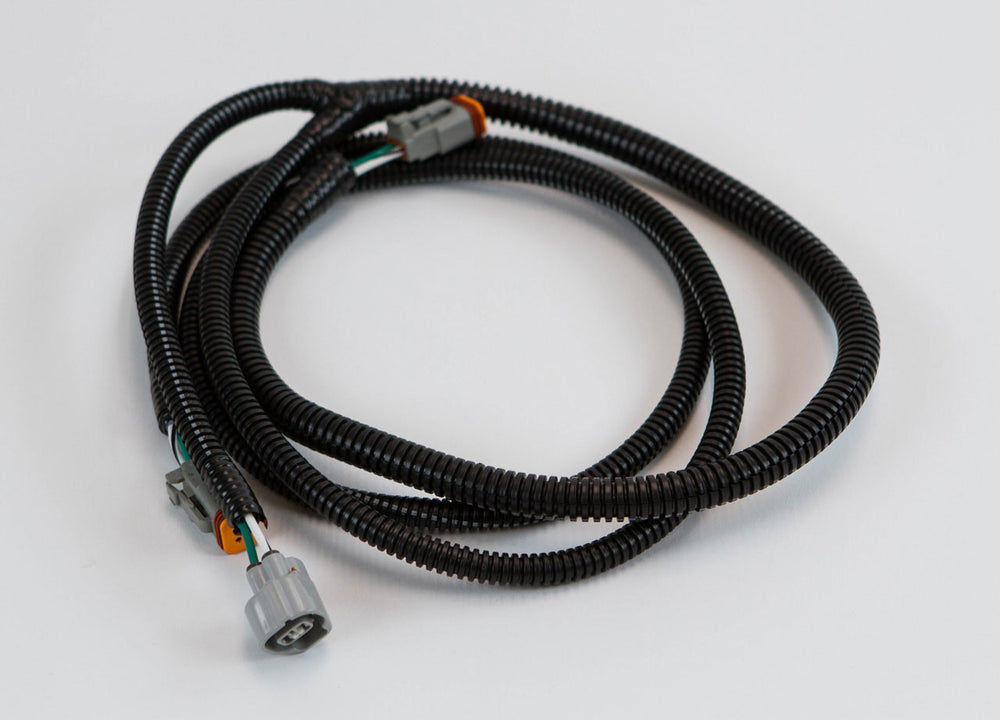 Coiled black plug-and-play LED wire harness with gray connectors for 2016 Toyota Tacoma installation.