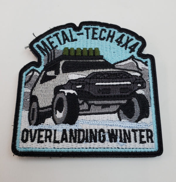 Embroidered patch showing a 4x4 truck in snowy mountains with "Metal-Tech 4x4 Overlanding Winter" text.