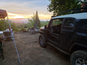 Black FJ Cruiser with installed metal tube doors parked at a campsite during sunset.