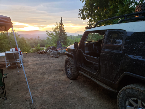 Black FJ Cruiser with installed metal tube doors parked at a campsite during sunset.