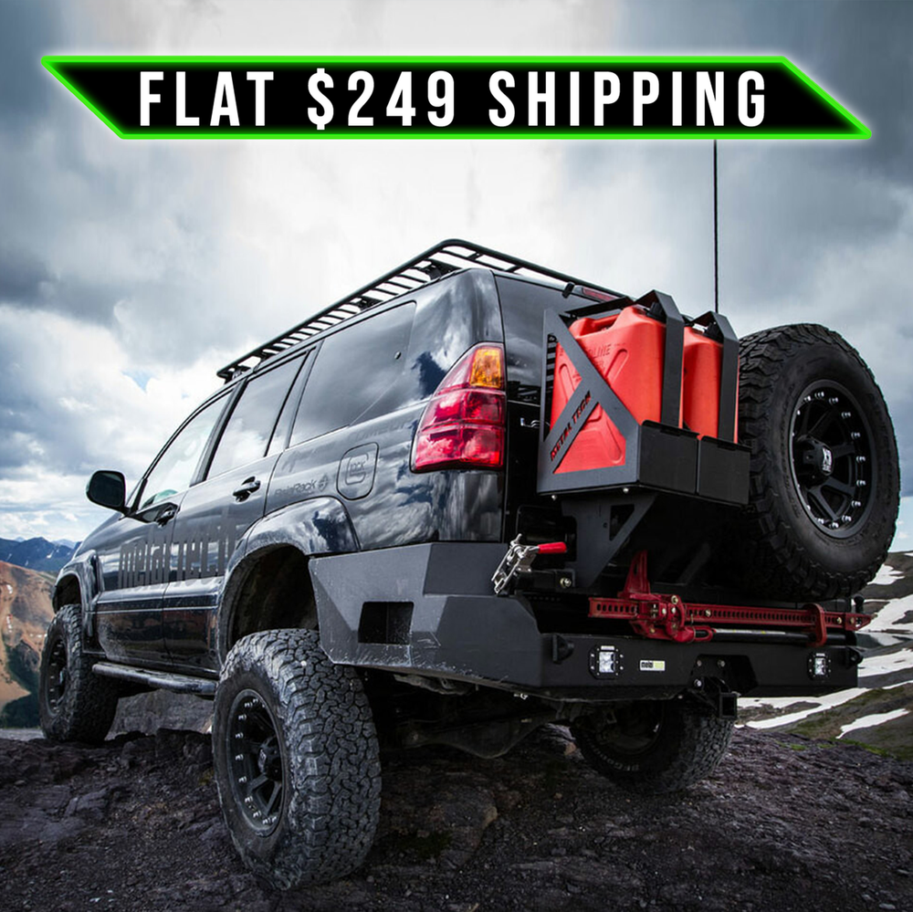 Off-road vehicle with installed Metal Tech Stage 1 rear bumper shell, spare tire, and fuel cans on rocky terrain.