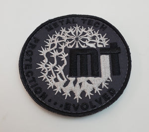 Round black and silver embroidered morale patch with "Metal Tech" text and abstract thorn design.