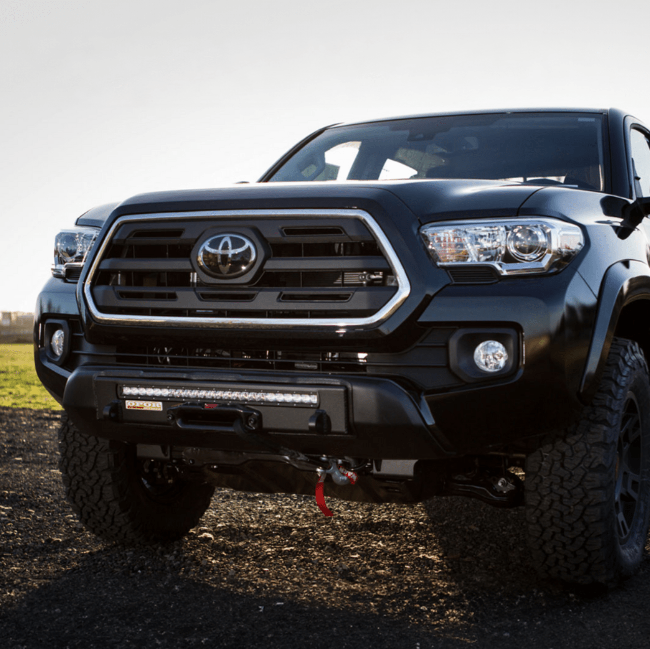 Front view of a black 2016 Toyota Tacoma with a Stronghold winch bumper and LED light bar installed.