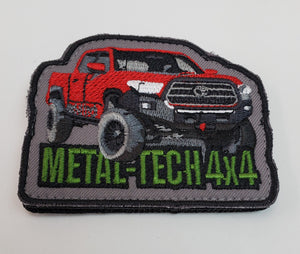 Embroidered patch showing a lifted red 4x4 Tacoma truck with "METAL-TECH 4x4" in green text on gray background.