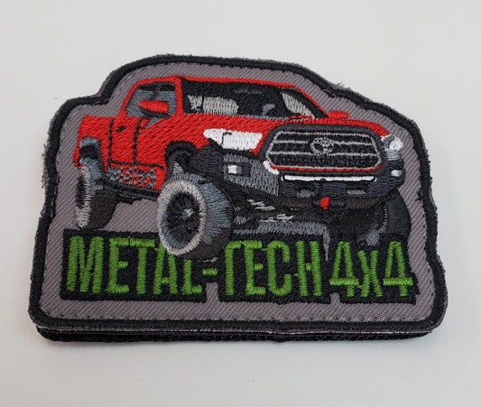 Embroidered patch showing a lifted red 4x4 Tacoma truck with "METAL-TECH 4x4" in green text on gray background.