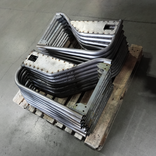 Stack of raw metal tube doors for FJ45 Land Cruiser on a wooden pallet in a warehouse setting.