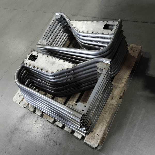 Stack of unfinished metal tube doors for FJ40 Land Cruiser on wooden pallet in workshop.