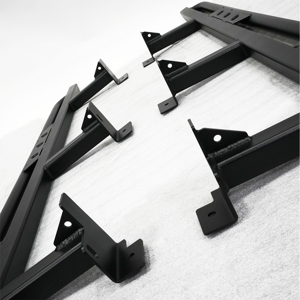 Close-up of black metal rock sliders with mounting brackets for 2016 Tacoma 4-door long bed installation.