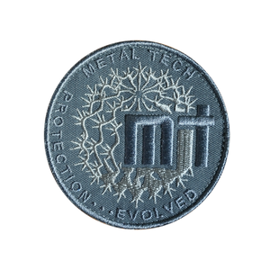 Round embroidered patch with "Metal Tech" text, abstract circuit design, and "Protection...Evolved" slogan in gray tones.