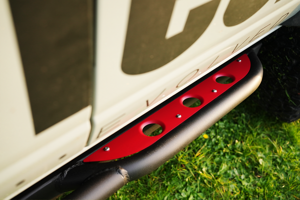 Close-up of red and black Sidewinder rock slider installed on 2021 Bronco 4-door, showing mounting details and texture.