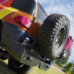 Close-up of Metal Tech Red Eye II full shell rear swing-out bumper with spare tire mounted on orange FJ Cruiser.