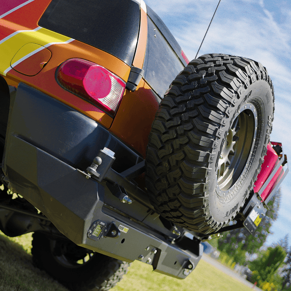 Close-up of Metal Tech Red Eye II full shell rear swing-out bumper with spare tire mounted on orange FJ Cruiser.
