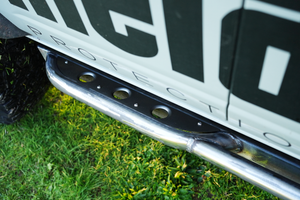 Close-up of polished steel Sidewinder rock slider with black step plate installed on 2021 Bronco 4-door side panel.