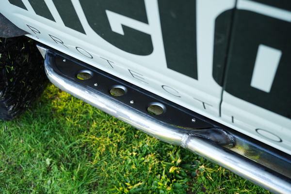 Close-up of polished steel Sidewinder rock slider with black step plate installed on 2021 Bronco 4-door side panel.